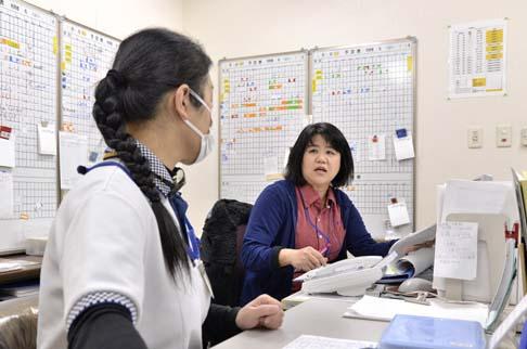 画像:パソコンの前で女性スタッフと会話している原田さんの様子。