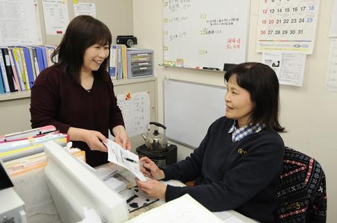 画像:女性のスタッフとパソコンの前で話している中島さんの様子。