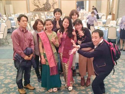 画像:円卓が並んでいる歓迎会の会場内で女性研修生2名を囲んで6名の職員と笑顔で映っている様子