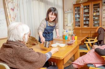 画像：室内で女性の利用者に食事の介護をされている渡邉さんの様子